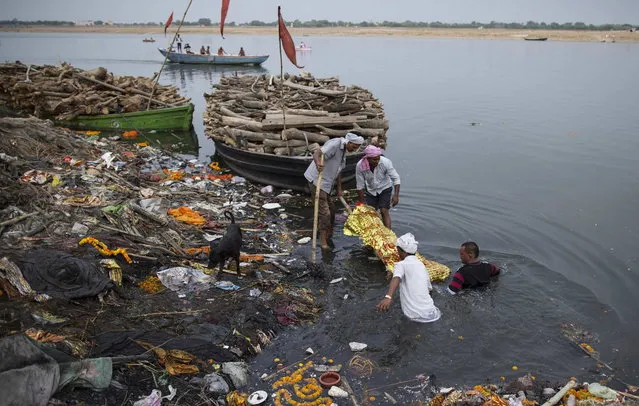 Relatives immerse a body in the river Ganges prior to cremation in Varanasi, in the northern Indian state of Uttar Pradesh, June 19, 2014. (Photo by Danish Siddiqui/Reuters)