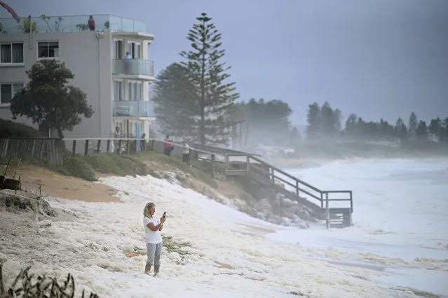 A resident inspects sea foam brought by waves approaching on beach front houses after heavy rain and storms at Collaroy in Sydney's Northern Beaches, Monday, February 10, 2020. Drought, wildfires and now flooding have given Australia's weather an almost Biblical feel this year. The good news is that a deluge in eastern parts of the country over recent days has helped dampen deadly fires and ease a crippling drought. (Photo by Joel Carrett/AAP Image via AP Photo)