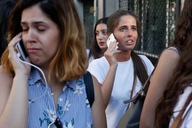 People phone to relatives or friends after a van ploughed into the crowd, killing one person and injuring several others on the Rambla in Barcelona on August 17, 2017. (Photo by Pau Barrena/AFP Photo)