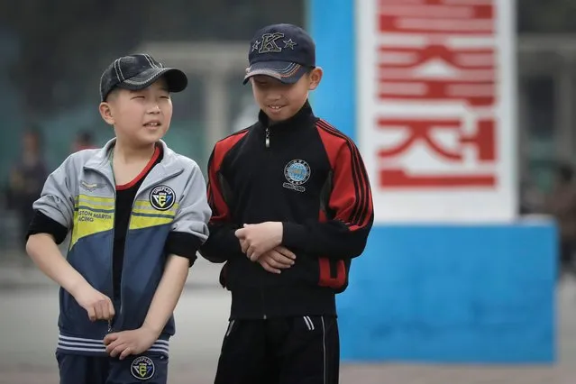 In this Sunday, April 16, 2017, photo, two young North Korean boys wearing baseball caps walk down a street in Pyongyang, North Korea. On the streets there are young women in not-quite mini-skirts and teenage boys with baseball hats cocked sideways, K-pop style. A generational divide is quietly growing in North Korea, often hidden behind relentless propaganda. (Photo by Wong Maye-E/AP Photo)