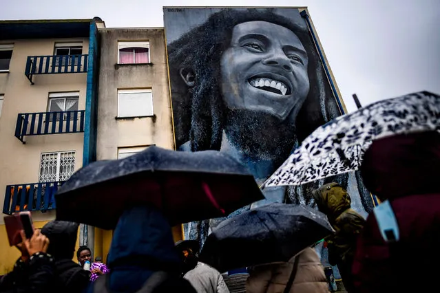 Visitors watch a mural by Portuguese artist Odeith depicting Jamaican singer Bob Marley during a guided visit to Quinta do Mocho neighbourhood in Sacavem, outskirts of Lisbon, on November 11, 2019. (Photo by Patricia De Melo Moreira/AFP Photo)