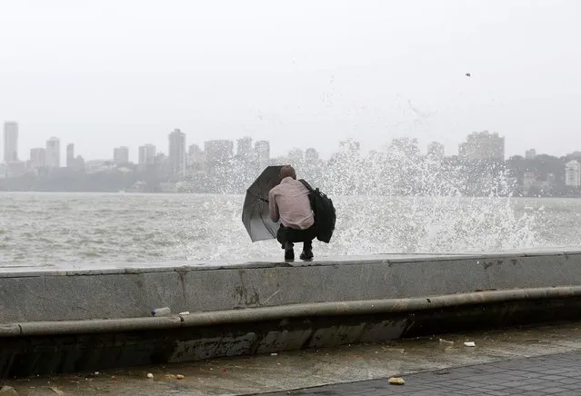A man uses his umbrella to shield himself from a wave during high tide at the sea front in Mumbai, India, July 5, 2016. (Photo by Shailesh Andrade/Reuters)