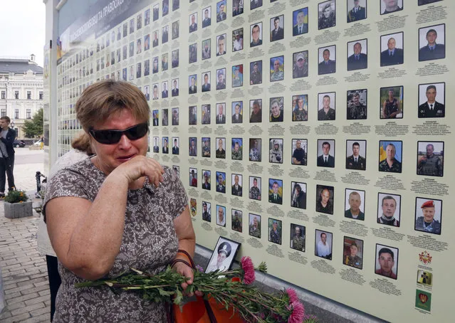 A woman cries at a memorial wall with photos of servicemen killed in the conflict with pro-Russian separatists in the country's east, in Kiev, Ukraine, Monday, August 28, 2017. Ukrainian President Petro Poroshenko said about 10,000 people, both servicemen and civilians, had been killed in the Donetsk region since 2014. (Photo by Efrem Lukatsky/AP Photo)