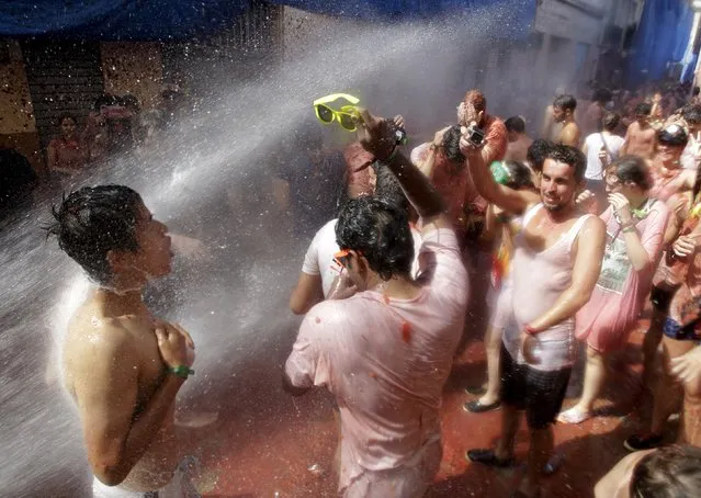 Revelers are sprayed with water after the annual “Tomatina” (tomato fight) in Bunol, near Valencia, Spain, August 26, 2015. (Photo by Heino Kalis/Reuters)