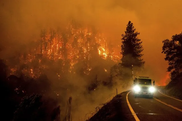A firetruck drives along California Highway 96 as the McKinney Fire burns in Klamath National Forest, Calif., Saturday, July 30, 2022. (Photo by Noah Berger/AP Photo)