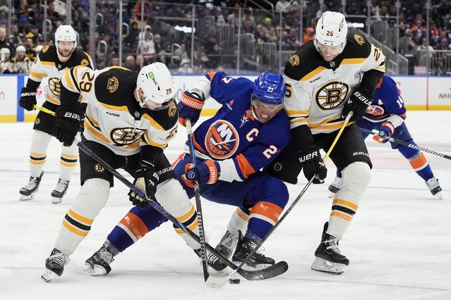 New York Islanders left wing Anders Lee (27), center, fight for the puck with Boston Bruins defensemen Parker Wotherspoon (29), left, and Brandon Carlo (25), right during the second period of an NHL hockey game, Wednesday, November 27, 2024, in Elmont, N.Y. (Photo by Julia Demaree Nikhinson/AP Photo)