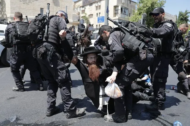 Riot policemen arrest an Ultra Orthodox Jewish protester in a religious neighbourhood in Jerusalem, 15 August 2022. Hundreds of protesters blocked roads during a demonstration against the police's decision to perform an autopsy of the body of a 4-year-old ultra-Jewish boy who allegedly was killed by a relative. As in Jewish religious tradition the body is regarded sacred, an autopsy – in case of a crime – is often the cause of controversy between investigating authorities and orthodox relatives of a victim. (Photo by Abir Sultan/EPA/EFE/Rex Features/Shutterstock)