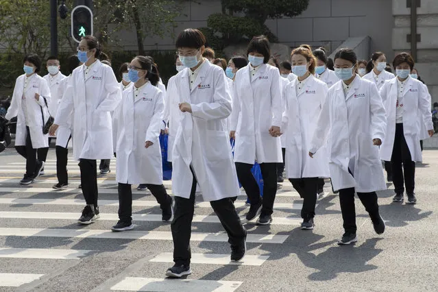 Medical workers from Beijing walk near a park during a day off as the city of Wuhan slowly loosens up ahead of a lifting of the two month long lockdown in central China's Hubei province on Sunday, April 5, 2020. The quarantine in the city which is the epicenter of China's coronavirus outbreak is to be formally lifted on Wednesday. (Photo by Ng Han Guan/AP Photo)