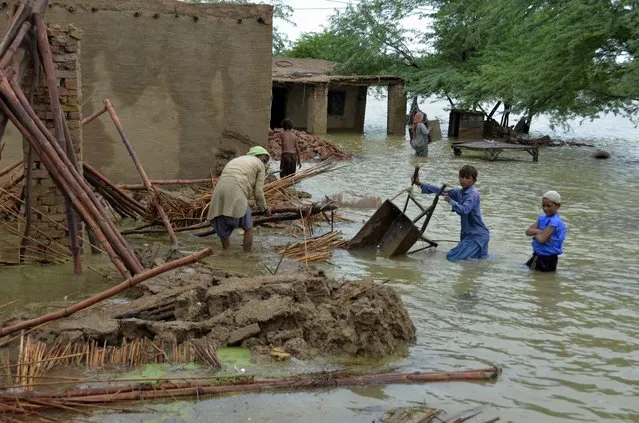A family salvage usable items from their flood-hit home in Jaffarabad, a district of Pakistan's southwestern Baluchistan province, Thursday, August 25, 2022. (Photo by Zahid Hussain/AP Photo)
