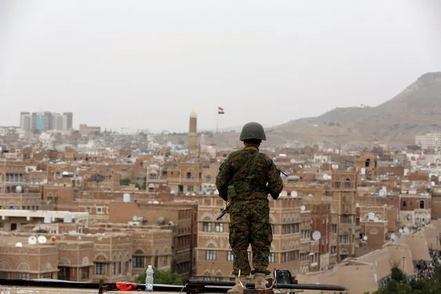 An army soldier loyal to the Houthi movement stands guard on the roof of a building overlooking the site of a demonstration against Saudi-led airstrikes in Sanaa, Yemen July 18, 2016. (Photo by Khaled Abdullah/Reuters)