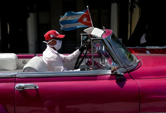 A private taxi driver on an old American car wears a face mask as a preventive measure against the spread of the new coronavirus, COVID-19, while driving tourists around Havana, on March 19, 2020. (Photo by Yamil Lage/AFP Photo)