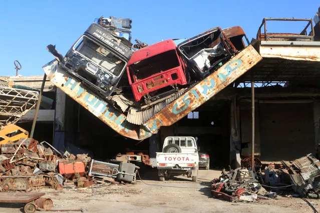 Damaged vehicles pile on a damaged roof of a car mechanic service center in Ramousah area southwest of Aleppo, Syria August 2, 2016. Picture taken August 2, 2016. (Photo by Abdalrhman Ismail/Reuters)