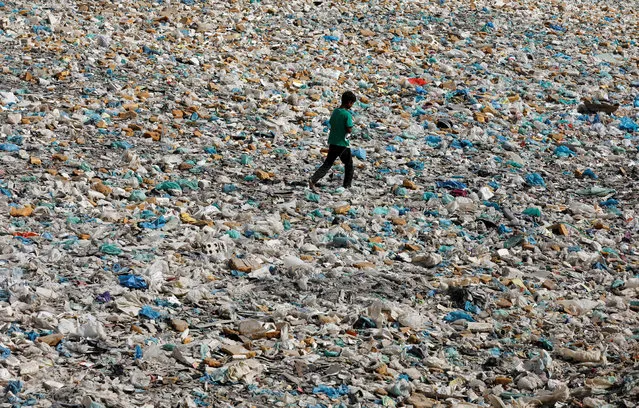 A boy walks over a drainage channel littered with heaps of polyethene bags on Earth Day, as the spread of the coronavirus disease (COVID-19) continues, in Karachi, Pakistan on April 22, 2020. (Photo by Akhtar Soomro/Reuters)