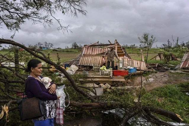 Mercedes Valdez holds her dog Kira as she waits for transportation after losing her home to Hurricane Ian in Pinar del Rio, Cuba, Tuesday, September 27, 2022. (Photo by Ramon Espinosa/AP Photo)