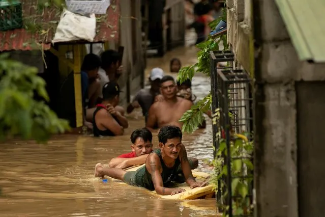 A man paddles through chest-deep flood waters with a surfboard after Super Typhoon Noru, in San Miguel, Bulacan province, Philippines on September 26, 2022. (Photo by Eloisa Lopez/Reuters)