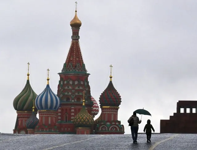 A woman and a child walk on Red Square in front of St. Basil's Cathedral in Moscow on October 3, 2022. (Photo by Yuri Kadobnov/AFP Photo)