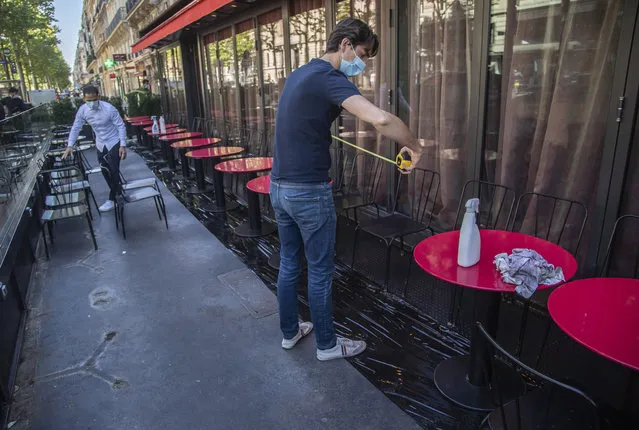 Pierre-Antoine Boureau handling a tape measure as he prepares the terrace of a restaurant in order to respect distancing to help curb the spread of the coronavirus in Paris, Monday, June 1, 2020. France is reopening its restaurants, bars and cafes starting tomorrow as the country eases most restrictions amid the coronavirus crisis. (Photo by Michel Euler/AP Photo)