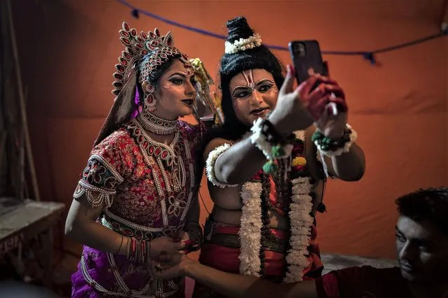 Artists dressed as Hindu god Ram and his wife Sita take a selfie before a final Ramleela performance as part of Dussehra festival celebrations in New Delhi, India, Wednesday, October 5, 2022. Ramleela is a dramatic folk re-enactment of the life of Hindu lord Rama. After the enactment of the legendary war between Good and Evil, the Ramleela celebrations climax in the Dussehra night festivities where the giant effigies of demon King Ravana, his brother Kumbakaran and son Meghnad are burnt, typically with fireworks. (Photo by Altaf Qadri/AP Photo)