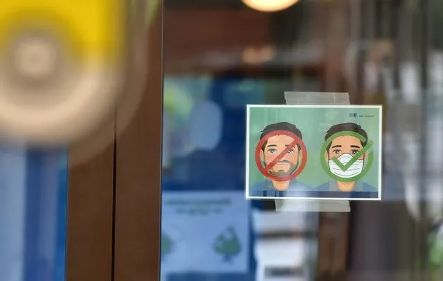 A poster asking to wear a mask is displayed on the entrance door of a classroom at a primary school in Eichenau, southern Germany, on June 16, 2020 amid the novel coronavirus COVID-19 pandemic. The pupils sit at a distance from each other and attend school in smaller classes until the summer holidays due to the pandemic. (Photo by Christof Stache/AFP Photo)