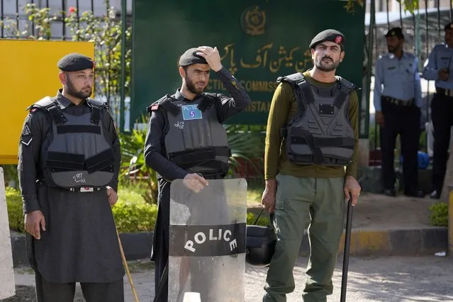 Police officers stand guard at the main entrance of the Election Commission head office in Islamabad, Pakistan, Friday, October 21, 2022. The elections commission on Friday disqualified Khan from holding public office on charges of unlawfully selling state gifts to him and concealing assets, his spokesman said. (Photo by Anjum Naveed/AP Photo)