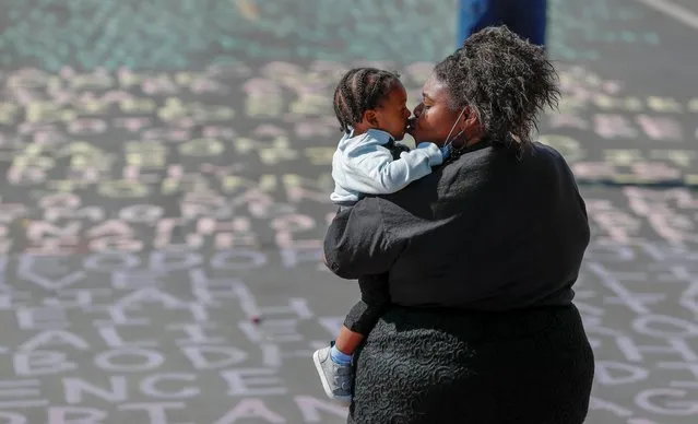 A woman kisses a child as they stand on a street painted with the names of people killed by police near the site of the arrest of George Floyd, who died while in police custody, in Minneapolis, Minnesota, U.S. June 14, 2020. (Photo by Eric Miller/Reuters)