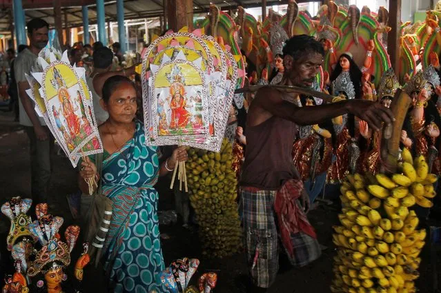 A vendor holds images of Hindu snake goddess Manasa at a market ahead of the Nag Panchami festival celebrations, in Agartala, India, August 16, 2016. (Photo by Jayanta Dey/Reuters)