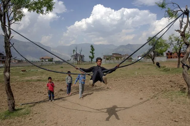 Kashmiri boys play on a makeshift swing on a hot summer day on the outskirts of Srinagar, Indian controlled Kashmir, Tuesday, June 16, 2020. Set in the Himalayas at 5,600 feet above sea level, Kashmir is a green, saucer-shaped valley surrounded by snowy mountain ranges with over 100 lakes dotting its highlands and plains. (Photo by Dar Yasin/AP Photo)
