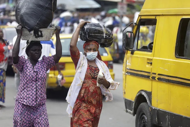 A woman wearing a face mask walks on the street, opposite the Central mosque in Lagos, Nigeria, Friday, March 20, 2020. The government banned all religious activities for four weeks following confirmation of coronavirus cases in the country. (Photo by Sunday Alamba/AP Photo)