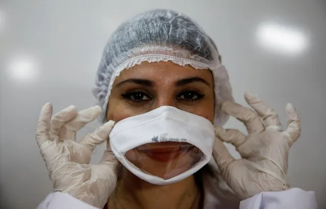 Avcilar Municipality's worker Sevim Ozek presents a protective face mask which allows lip reading, designed by Mayor Turan Hancerli for families who have hearing impaired members, in Istanbul, Turkey on May 27, 2020. (Photo by Umit Bektas/Reuters)