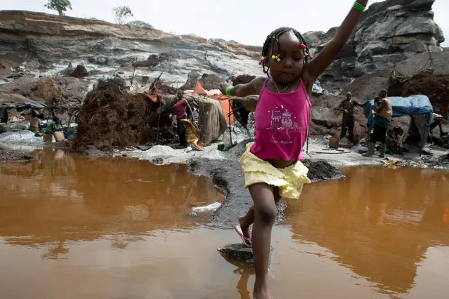 Melissa Kabore, 4, jumps over a puddle in Pissy informal granite quarry in Ouagadougou, Burkina Faso June 12, 2020. At an open-pit granite quarry in Burkina Faso's capital, workers' children play in the rubble while others toil alongside their parents after the coronavirus pandemic closed schools. (Photo by Anne Mimault/Reuters)