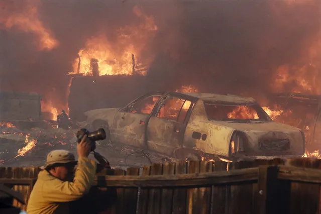 A news photographer takes pictures of a wildfire in the Lake View Terrace area of Los Angeles, Tuesday, December 5, 2017. (Photo by Chris Carlson/AP Photo)