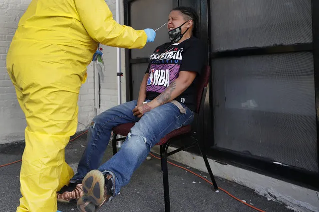 Naliber Tavares winces as she receives a COVID-19 test at the Whittier Street Health Center's mobile test site, Wednesday, July 15, 2020, in Boston's Dorchester section. The health center has administered free COVID-19 tests to over 5,000 people. The tests, administered since April 13, have been a popular service in Boston's low-income communities that have experienced high rates of infection. (Photo by Elise Amendola/AP Photo)