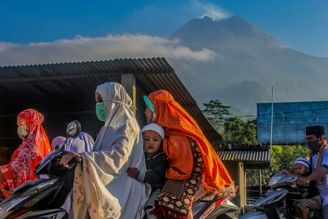 Muslims walk home after completing the Eid al-Adha prayer against the background of Mount Merapi which emits sulfatara smoke in Cangkringan, Sleman, Yogyakarta, Friday, July 31, 2020. Muslims in Indonesia congregate by implementing health protocols to prevent the spread of COVID-19. (Photo by Slamet Riyadi/Zuma/Rex Features/Shutterstock)