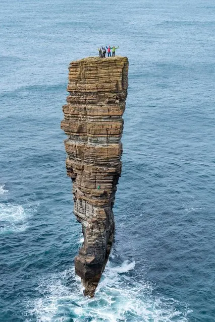 Victory salute from the summit in Orkney. (Photo by Dave Cuthbertson/Caters News Agency)