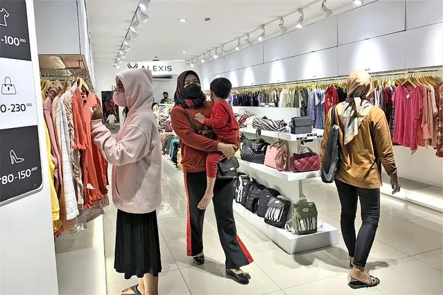 People wearing face mask browse for clothings at a shopping mall in Jakarta, Indonesia, Friday, December 30. 2022. Almost three years after officials announced the first confirmed case of COVID-19 in Indonesia, the country’s leader said Friday they are lifting all coronavirus-related restrictions nationwide. (Photo by Tatan Syuflana/AP Photo)
