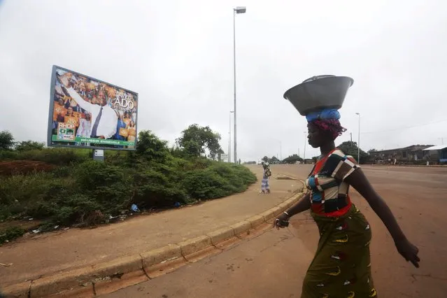 A woman walks past a campaign billboard of presidential candidate Alassane Ouattara of the ruling RHDP coalition in Yamoussoukro, Ivory Coast October 11, 2015. (Photo by Thierry Gouegnon/Reuters)