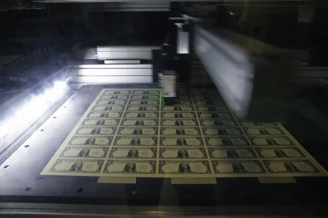 A sheet of one dollar bills is scanned for quality during production at the Bureau of Engraving and Printing in Washington November 14, 2014. (Photo by Gary Cameron/Reuters)