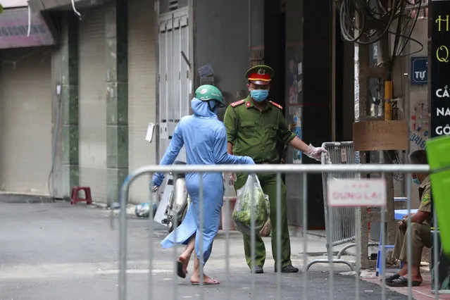 A woman leaves the food shopping for her relatives at the barricaded entrance to the residence of a confirmed COVID-19 case in Hanoi, Vietnam on Wednesday, July 29, 2020. Vietnam intensifies protective measures as the number of locally transmissions, starting at a hospital in the popular beach city of Da Nang, keeps increasing since the weekend. (Photo by Hau Dinh/AP Photo)