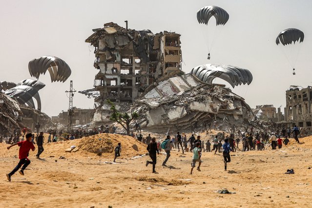 People rush to landing humanitarian aid packages dropped over the northern Gaza Strip on April 23, 2024 amid the ongoing conflict in the Palestinian territory between Israel and the militant group Hamas. (Photo by AFP Photo/Stringer)