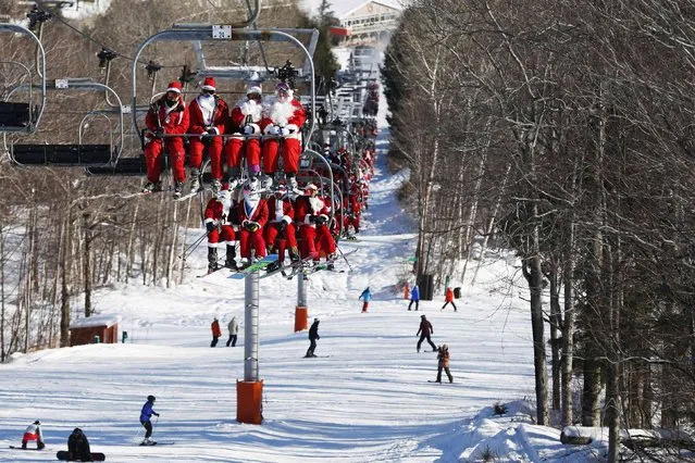 Skiers and snowboarders dressed as Santa Claus ride the chair lift to participate in a charity run down a slope at Sunday River Ski Resort in Newry, Maine December 7, 2014. (Photo by Brian Snyder/Reuters)