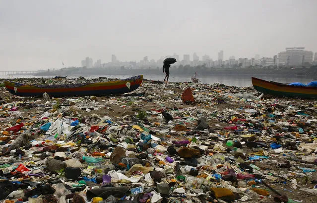 A fisherman walks on the shores of the Arabian Sea, littered with plastic bags and other garbage, in Mumbai, India, Sunday, October 2, 2016. India is scheduled to deposit the ratification instruments of the Paris Agreement on Climate Change with the United Nations on Sunday, the anniversary of Mahatma Gandhi's birth, who believed in a minimum carbon footprint. India accounts for about 4.5 percent of emissions. (Photo by Rafiq Maqbool/AP Photo)