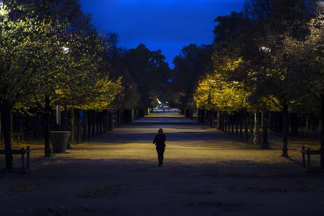 A woman walks by the empty Tuileries gardens in the center of Paris, Friday, October 30, 2020. (Photo by Lewis Joly/AP Photo)