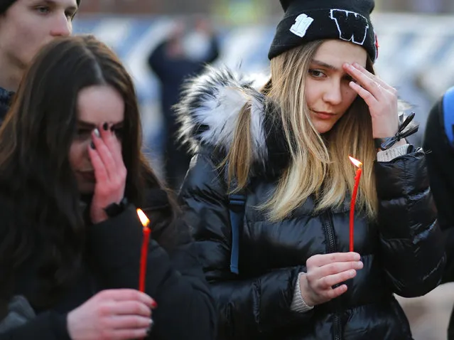 People hold the candles to commemorate the victims of Sunday's fire in a shopping mall in the Siberian city of Kemerovo, in the center of Moscow, on Tuesday, March 27, 2018. Several Russian cities including Moscow are holding rallies to commemorate the dead. (Photo by Alexander Zemlianichenko/AP Photo)