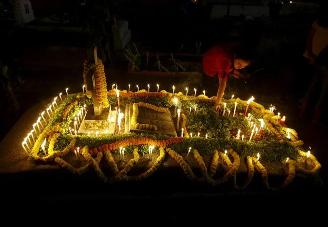 A girl places incense sticks on the grave of her relative at a cemetery during the observance of All Souls Day in Kolkata November 2, 2015. (Photo by Rupak De Chowdhuri/Reuters)