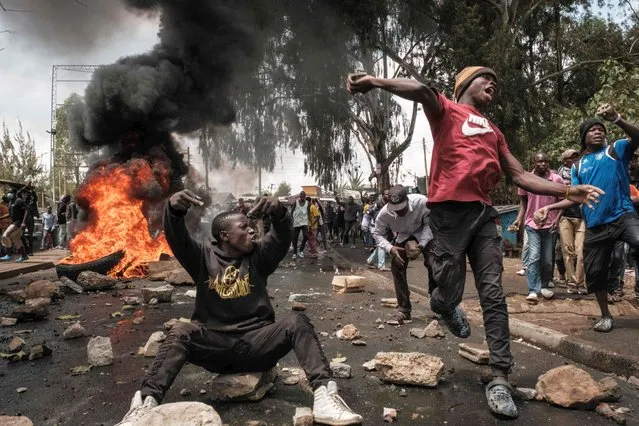 Protesters throw stones towards police officers and a water cannon vehicle during a mass rally called by the opposition leader Raila Odinga who claims the last Kenyan presidential election was stolen from him and blames the government for the hike of living costs in Kibera, Nairobi on March 20, 2023. (Photo by Yasuyoshi Chiba/AFP Photo)