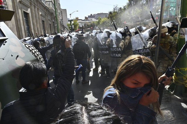 A woman walks away from tear gas fired by military troops in La Paz, Bolivia, on Wednesday, June 25, 2024. A Bolivian general was arrested and accused of mounting a coup against the government after attempting to storm the presidential palace on Wednesday. (Photo by Aizar Raldes/AFP Photo)