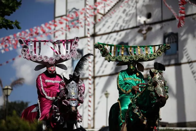 Horsemen wearing elaborate bull masks ride past Our Lady of the Rosary church during the “Cavalhadas” festival in Pirenopolis, Brazil, Sunday, May 19, 2013. The popular festival, featuring masked horsemen, is a tradition that was introduced in the 1800's by a Portuguese priest to mark the the ascension of Christ. The 3-day festival reenacts the Christian knights' medieval defeat of the Moors. (Photo by Eraldo Peres/AP Photo)