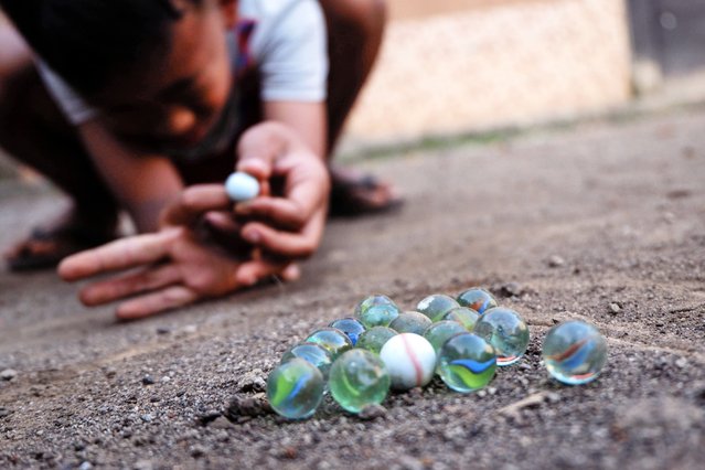 Children play marbles on the dirt in Garut, West Java, Indonesia on October 17, 2025. This traditional game, which was popular in the 1980s, is now rarely played by children due to the increasing popularity of modern games with advanced technology. According to a survey by the Indonesian Child Protection Commission (KPAI), more than 71.3% of school-age children own gadgets and play them for a considerable amount of time each day, and as many as 79% of child respondents are allowed to play gadgets for purposes other than learning. (Photo by Algi Febri Sugita/ZUMA Press Wire/Rex Features/Shutterstock)