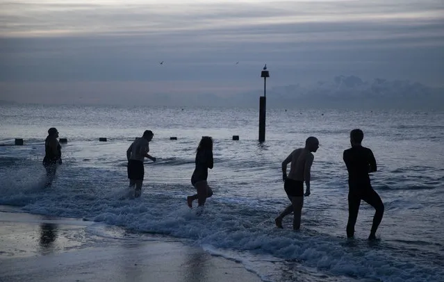 Swimmers make their way into the sea at Boscombe beach in Boscombe, United Kingdom on January 22, 2021 before sunrise. Temperatures could drop as low as –10°C (14°F) in the coming days, as Storm Christoph gives way to colder winter weather this weekend. (Photo by Andrew Matthews/PA Images via Getty Images)