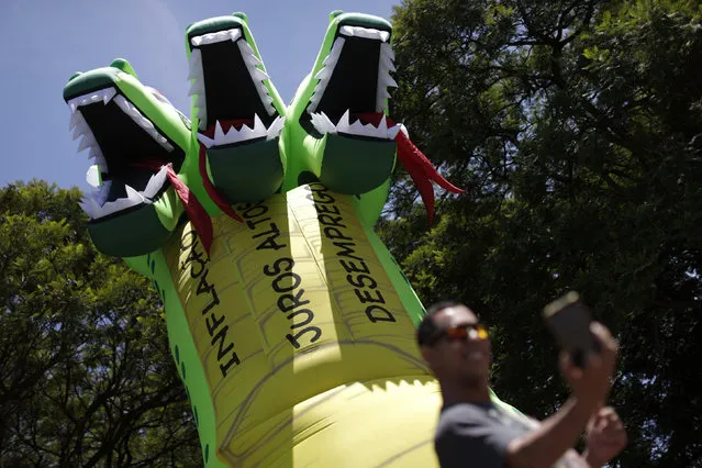 A man takes a selfie in front of a giant inflatable doll in the shape of a thirteen meters high, three-headed dragon, during a protest against inflation, unemployment and high interest rates in downtown Brasilia, Brazil December 1, 2015. (Photo by Ueslei Marcelino/Reuters)